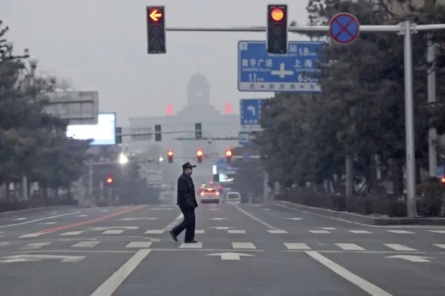 A man walks across an empty road during the fourth day of a city wide lock down in Changchun in northeastern China's Jilin province Monday, March 14, 2022. (Photo by Chinatopix via AP Photo)