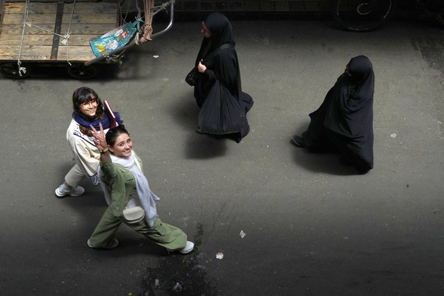 An Iranian woman without wearing her mandatory Islamic headscarf flashes a victory sign as two head-to-toe veiled women walk at the old main bazaar of Tehran, Iran, Thursday, June 13, 2024. (Photo by Vahid Salemi/AP Photo)
