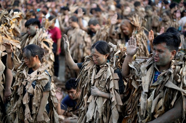 Devout Catholics, dressed in dried banana leaves, pray outside the church of Saint John the Baptist during the mud festival at Bibiclat, Nueva Ecija province, northern Philippines, Monday, June 24, 2024. (Photo by Aaron Favila/AP Photo)