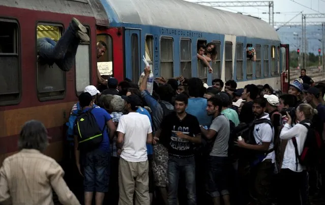 Migrants try to get onboard an overloaded International train, from Thessaloniki to Budapest at Gevgelija train station in Macedonia, near the border with Greece, on their transit route to Europe,  July 19, 2015. (Photo by Ognen Teofilovski/Reuters)