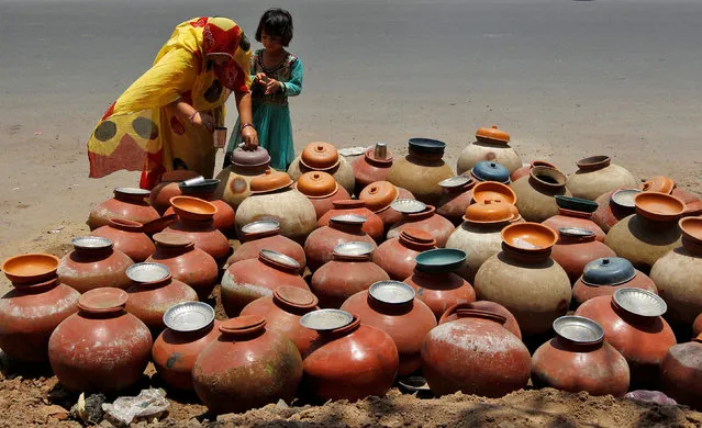 A woman gets a drink of water from an earthenware pot at a public water station in Ahmedabad, India May 20, 2016. (Photo by Amit Dave/Reuters)