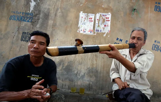 A man smokes a bamboo pipe while chatting with his friend on a street in Hanoi, Vietnam May 10, 2017. (Photo by Reuters/Kham)