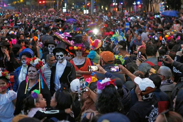 People dressed as Catrinas parade down Mexico City's iconic Reforma avenue during celebrations for the Day of the Dead in Mexico, City, Saturday, October 26, 2019. (Photo by Ginnette Riquelme/AP Photo)