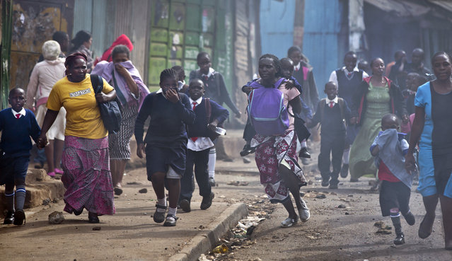 Women and schoolchildren take advantage of a lull in the clashes to run to safety, as police firing tear gas engage protesters throwing rocks in the Kibera slum of Nairobi, Kenya Monday, May 23, 2016. (Photo by Ben Curtis/AP Photo)