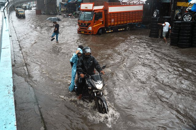 A motorist rides through a waterlogged street as it rains In Mumbai, India, Thursday, July 25, 2024. (Photo by Rafiq Maqbool/AP Photo)