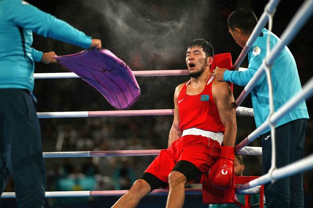 Kazakhstan's Nurbek Oralbay receives instructions from the coach during the break while competing against Ukraine's Oleksandr Khyzhniak (Blue) in the men's 80kg final boxing match during the Paris 2024 Olympic Games at the Roland-Garros Stadium, in Paris on August 7, 2024. (Photo by Mauro Pimentel/AFP Photo)