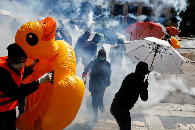 Demonstrators protect themselves with umbrellas amid tear gas during the traditional May Day labour march, a day of mobilisation against the French pension reform law and for social justice, in Nantes, France on May 1, 2023. (Photo by Stephane Mahe/Reuters)