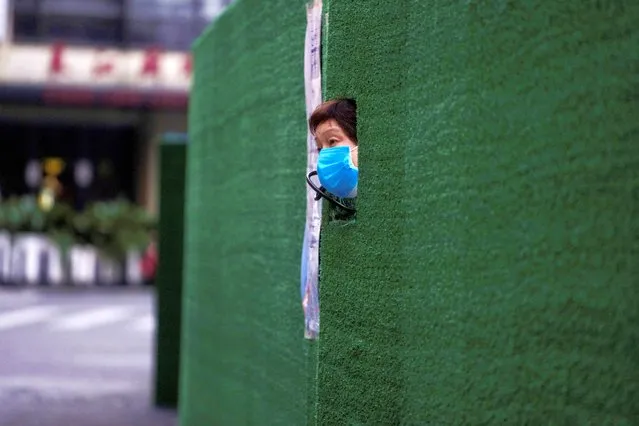 A resident looks out through a gap in the barrier at a residential area during lockdown, amid the coronavirus disease (COVID-19) pandemic, in Shanghai, China, May 6, 2022. (Photo by Aly Song/Reuters)