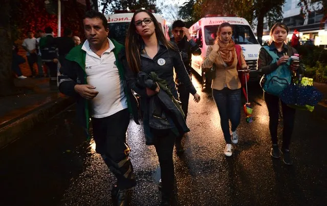 A woman is escorted by a medic following an explosion inside a mall which -according to authorities- left one dead and eleven injured, in Bogota, Colombia, on June 17, 2017. (Photo by Raul Arboleda/AFP Photo)
