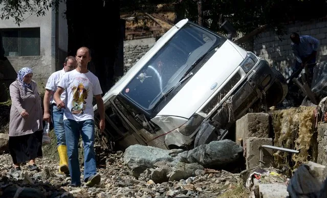 People walk along a street in the flooded village of Shipkovitsa, near the town of Tetovo, Macedonia, August 4, 2015. Four people including a seven-year-old child were killed and one person is still missing after heavy rain caused flash floods and mudslides in several villages in western Macedonia, police said on Tuesday. (Photo by Reuters/Stringer)