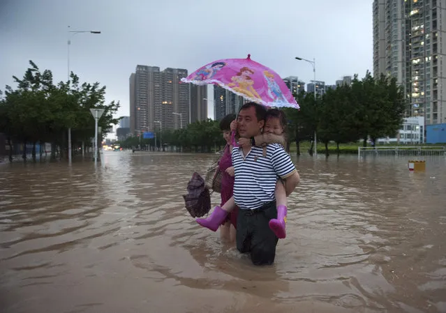 A man carries a girl as he walks along a flooded street in Shenzhen, Guangdong province, May 11, 2014. According to Xinhua News Agency, heavy rainstorm battering south China since last week has killed three people. (Photo by Reuters/Stringer)