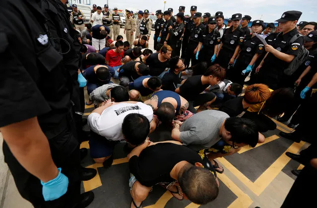 Taiwan's and China's suspects are surrounded by China police SWAT team and Cambodia police before being deported at the International Airport of Phnom Penh, June 24, 2016. Scores of Chinese police officers swarmed the tarmac at Phnom Penh International Airport on Friday as 39 suspects arrested for their involvement in an alleged telecom scam were herded onto a chartered plane bound for China – including 25 Taiwanese nationals, whose government unsuccessfully attempted to have them repatriated. (Photo by Samrang Pring/Reuters)