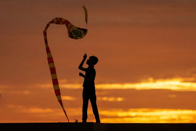A boy is seen in silhouette as he flies a kite in Colombo, Sri Lanka on December 1, 2019. (Photo by Dinuka Liyanawatte/Reuters)