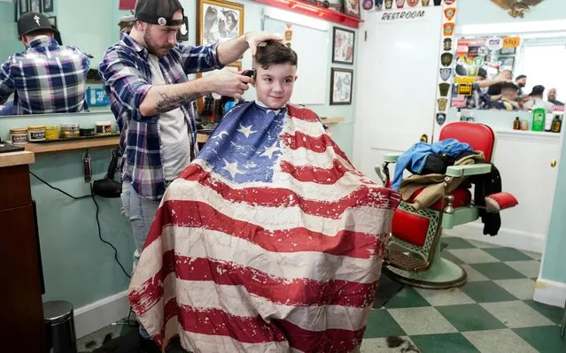As Democratic presidential candidates canvass the state, Nolan Pelletier wears a cape of stars and stripes for a haircut on his 10th birthday at the Parliament Barber Shop in Manchester, New Hampshire, U.S., February 8, 2020. (Photo by Kevin Lamarque/Reuters)