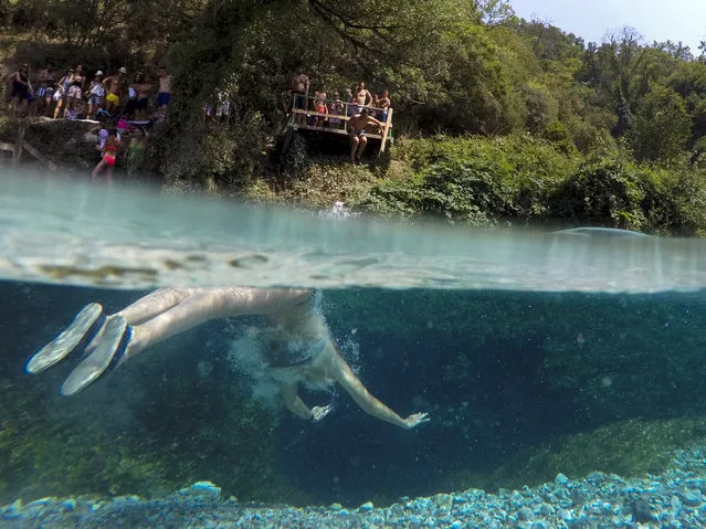 A man swims to cool off in the Blue Eye water spring and natural phenomenon occurring near the city of Sarande, Albania on August 16, 2017. The clear water of the Blue Eye spring flows from a pool which is over 50 meters deep and with a temperature of 10 degrees Celsius. (Photo by Gent Shkullaku/AFP Photo)