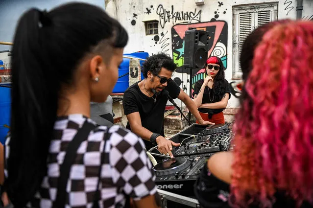 Experienced Cuban DJ Xander Black (C), 46, teaches a female-only DJ course on a rooftop in Havana, the first in 10 years, on May 30, 2022. Although the DJ scene in Cuba is fundamentally male, women have begun to gain ground based on talent and effort. (Photo by Yamil Lage/AFP Photo)