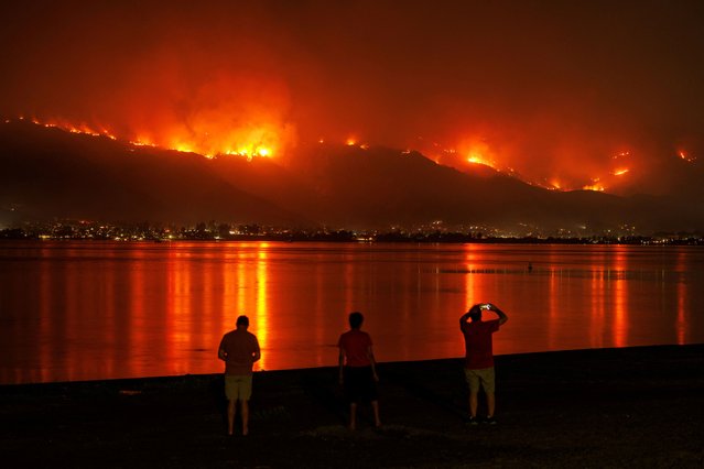 The Airport Fire burns along the hillside as residents watch from the shoreline in Lake Elsinore, California on September 10, 2024. (Photo by Mike Blake/Reuters)