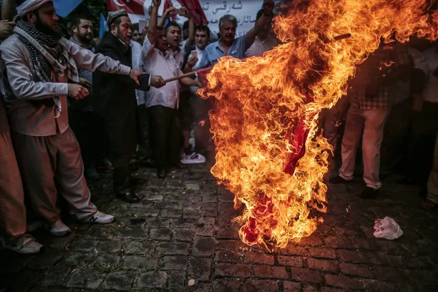 Uighurs living in Turkey set on fire a representation of a Chinese flag outside the Chinese consulate in Istanbul, Turkey, Saturday, Aug. 2, 2014, as they stage a protest to condemn the killings of Uighurs allegedly killed by Chinese security in China's far-western Xinjiang Uighur Autonomous Region. The blue flag with a white star and a crescent represents Eastern Turkistan. (Photo by Emrah Gurel/AP Photo)