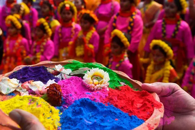 A participant holds a tray of coloured powder as students take part in a cultural procession to celebrate Holi, the spring festival of colours, in Kolkata on March 9, 2020. Holi is observed in India at the end of the winter season on the last full moon of the lunar month. (Photo by Dibyangshu Sarkar/AFP Photo)