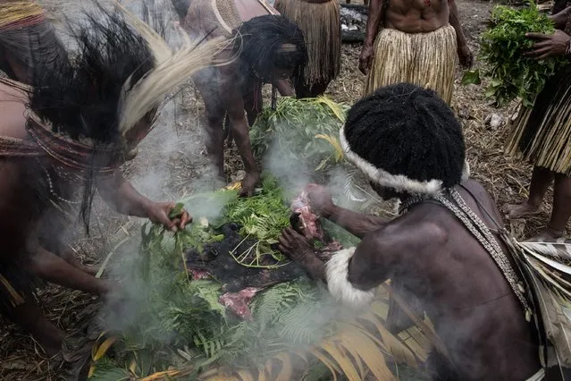 People from the Dani tribe cook a pig, vegetables and sweet potatoes in a traditional way, using hot stones, at Obia Village on August 9, 2014 in Wamena, Papua, Indonesia. (Photo by Agung Parameswara/Getty Images)