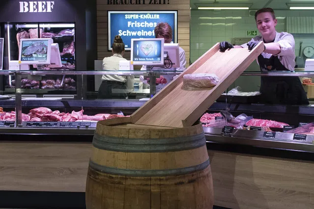 Marvin Gatzemeier, an employee in an Edeka market, stands behind a meat counter where a self-made “parcel slide” has been installed in Duderstadt, Germany Wednesday, March 25, 2020. With the help of the self-built slide, direct contact when handing over the packaged sausages is to be avoided. The public life is massively affected by measures to contain the new coronavirus. (Photo by Swen Pfortner/dpa via AP Photo)