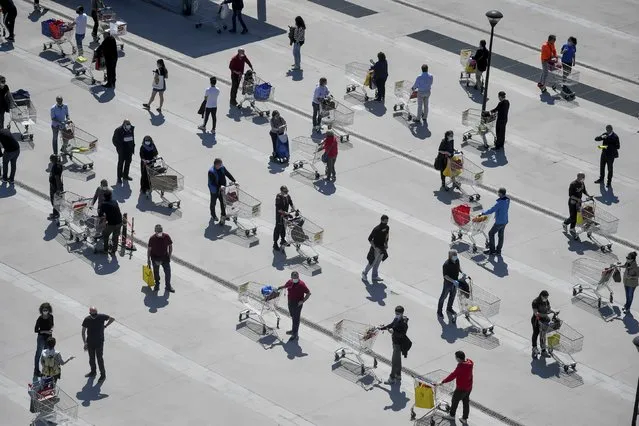 People stand in long lines waiting to enter at the Esselunga supermarket in San Donato, in the outskirts of Milan, Italy, Saturday, April 11, the day before Easter, when most Italian will try to mitigate the boredom of the coronavirus lockdown with the traditional lunch. (Photo by Claudio Furlan/LaPresse via AP Photo)