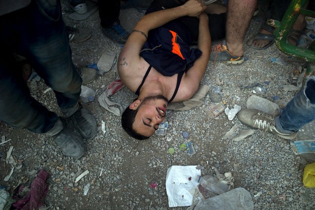 A young man collapses as he lines up with other migrants for a registration procedure at the port of Mytilene on the Greek island of Lesbos, September 3, 2015. (Photo by Dimitris Michalakis/Reuters)