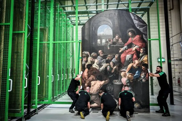 Workers carry a painting at the Notre-Dame de Paris cathedral paintings' restoration site on the outskirts of Paris, on September 6, 2022. (Photo by Stephane de Sakutin/AFP Photo)