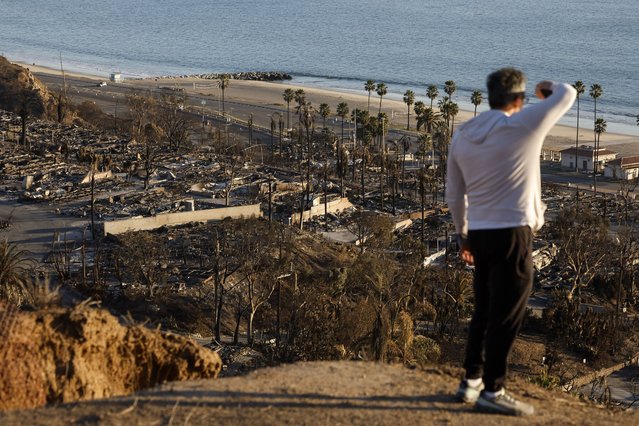 A person looks out over the remains of a burned down neighborhood in the Pacific Palisades neighborhood in Los Angeles, California, USA, 15 January 2025. According to the National Weather Service, much of Southern California is under an elevated fire risk, as the Santa Ana winds have returned and are predicted to affect the area. The Los Angeles County Medical Examiner's Office has stated that the suspected death toll from the Los Angeles fires now stands at 25 as search and rescue teams, both local and abroad, search the affected fire areas. (Photo by Caroline Brehman/EPA/EFE)