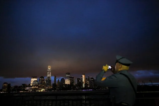 A New Jersey Police Officer takes pictures at sunrise across from New York's Lower Manhattan and One World Trade Center, in Liberty State Park in Jersey City, New Jersey, September 11, 2015. (Photo by Eduardo Munoz/Reuters)