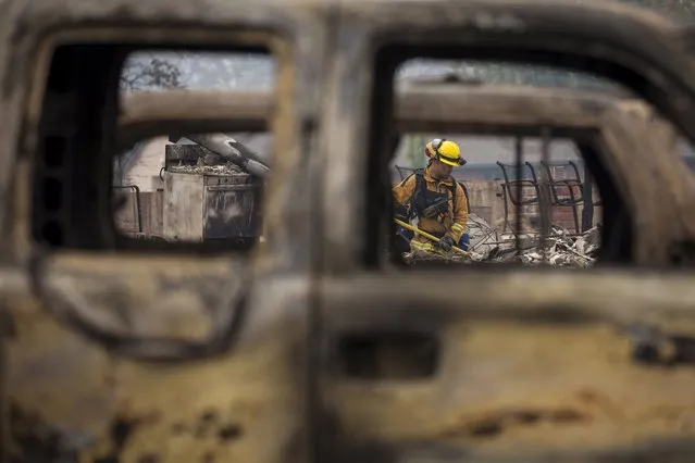 A firefighter is seen through destroyed cars as he searches for victims in the rubble of a home burnt by the Valley Fire in Middletown, California, September 14, 2015. (Photo by David Ryder/Reuters)