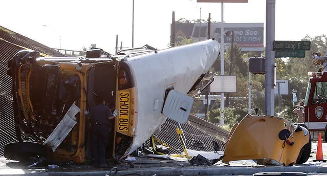 An emergency responder looks inside a school bus after the bus went off a Houston freeway and rolled, in southeast Houston, Tuesday, September 15, 2015, killing two students and seriously injuring three other people, police and school officials said. (Photo by Cody Duty/Houston Chronicle via AP Photo)
