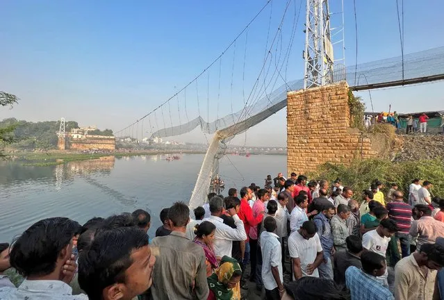 People gather as rescuers search for survivors after a suspension bridge collapsed in Morbi town in the western state of Gujarat, India on October 31, 2022. (Photo by Reuters/Stringer)