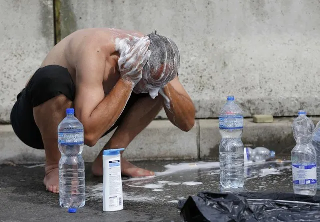 A migrant washes his hair at the Croatia-Slovenia border crossing at Bregana, Croatia, September 20, 2015. (Photo by Laszlo Balogh/Reuters)