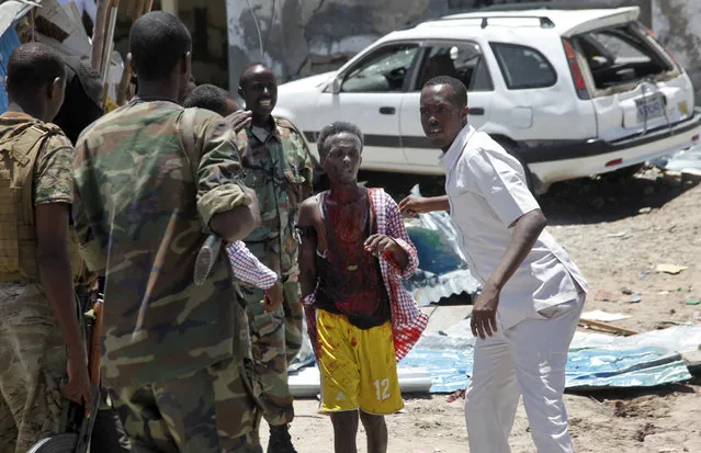 Somali soldiers help a man, center, who was wounded by a blast near the presidential palace in the capital Mogadishu, Somalia, Tuesday, August 30, 2016. A suicide bomber has detonated an explosives-laden truck near the gate of Somalia's presidential palace in the capital on Tuesday, killing at least five people, police say. (Photo by Farah Abdi Warsameh/AP Photo)