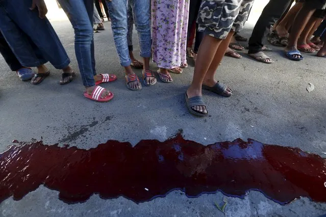 Muslims stand in a line near cow blood after it was slaughtered, as they wait to receive meat distributed to the poor at Matraman mosque of Jakarta September 24, 2015. (Photo by Reuters/Beawiharta)