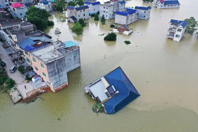 A three-storey house falls down in flood water on July 13, 2020 in Poyang County, Jiangxi Province of China. The water level of Poyang Lake rose due to continuous downpours. (Photo by Liu Zhankun/China News Service via Getty Images)