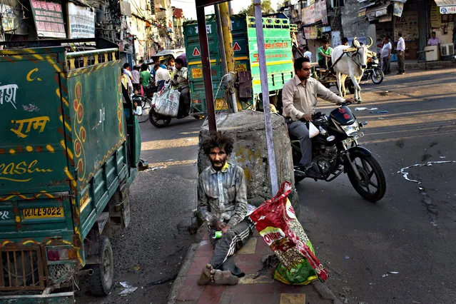 A homeless Indian man sits at a traffic intersection in the morning in New Delhi, India, Wednesday, September 30, 2015. Hundreds of millions of Indians still live on less than $2 a day. The United Nations global goals for sustainable development in the next fifteen years, seeks to end poverty in all its forms everywhere. (Photo by Bernat Armangue/AP Photo)