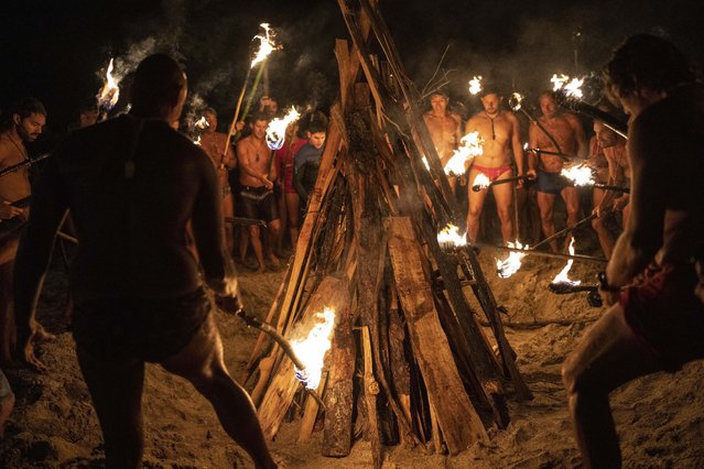 Lifeguards start a bonfire with torches to commemorate Lifeguard Day, to honor their commitment to safety and aquatic rescue, in Mar Azul, Argentina, Wednesday, February 14, 2024. (Photo by Rodrigo Abd/AP Photo)