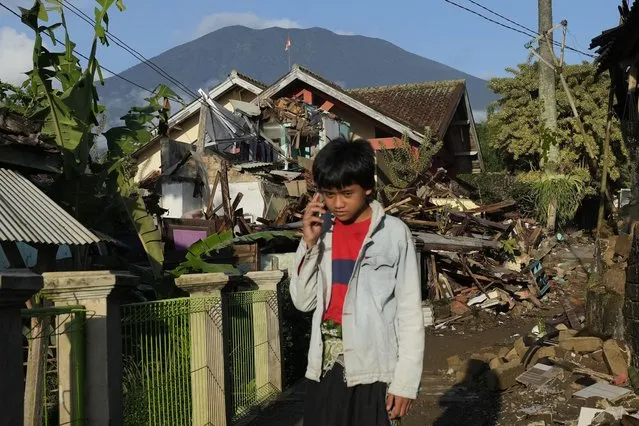A boy talks on his mobile phone near houses damaged in Monday's earthquake in Cianjur, West Java, Indonesia, Thursday, November 24, 2022. The 5.6 magnitude earthquake left hundreds dead, injures and missing as buildings crumbled and terrified residents ran for their lives on Indonesia's main island of Java. (Photo by Tatan Syuflana/AP Photo)