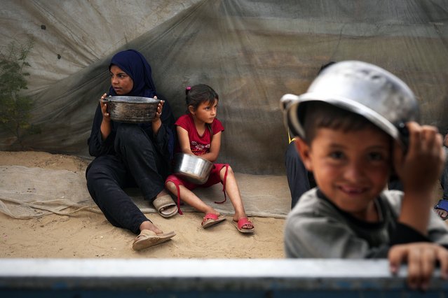 Raghad and her younger sister Mira hold on to their cooking pots as they wait to fill them with food, in Muwasi, on the outskirts of Khan Younis, in the southern Gaza Strip, April 24, 2025. (Photo by Abdel Kareem Hana/AP Photo)