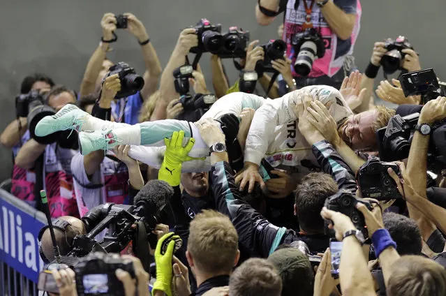 Mercedes driver Nico Rosberg of Germany is embraced by his team after winning the Singapore Formula One Grand Prix on the Marina Bay City Circuit Singapore, Sunday, September 18, 2016. (Photo by Wong Maye-E/AP Photo)