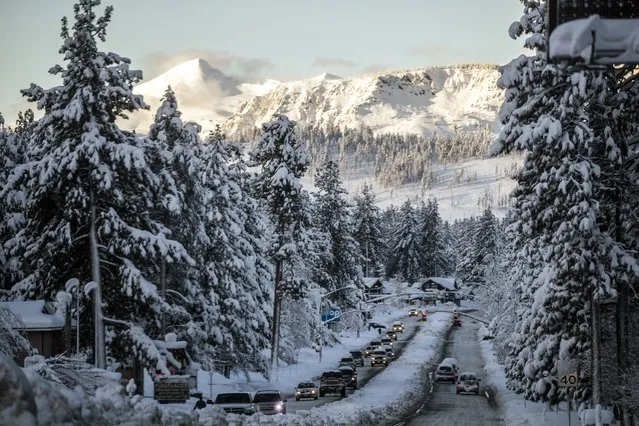 Vehicles travel along a snow-lined U.S. Route 50 the morning after a winter storm pelted the region with a large amount of snow, in South Lake Tahoe, Calif., Sunday, January 1, 2023. (Photo by Stephen Lam/San Francisco Chronicle via AP Photo)
