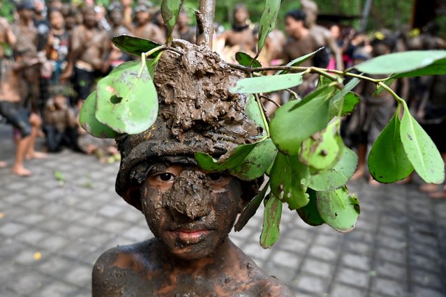 A Balinese boy takes part in a mud bath tradition, known as Mebuug-buugan, held a day after Nyepi – the Balinese “Day of Silence” – aimed at neutralising bad traits, in the village of Kedonganan, on Indonesia's resort island of Bali on March 12, 2024. (Photo by Sonny Tumbelaka/AFP Photo)