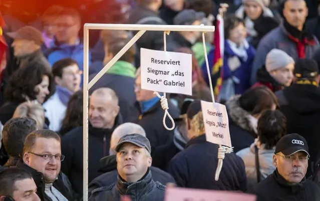 People hold up a mock hangman's gallows with a sign reading 'Reserved for Sigmar Gabriel' (L) and  'Reserved for Angela Merkel' as they gather for an anti-immigration demonstration organised by rightwing movement Patriotic Europeans Against the Islamisation of the West (PEGIDA) in front of the Palace Church in Dresden, Germany October 12, 2015. Sigmar Gabriel is the German minister of Econom. (Photo by Hannibal Hanschke/Reuters)