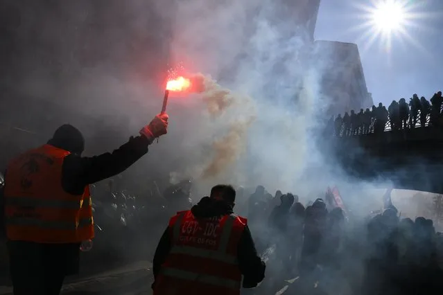A protester waves a light flare during a rally called by French trade unions against the government pension reform plan in Marseille, southern France, on January 19, 2023. A day of strikes and protests kicked off in France on January 19, 2023 set to disrupt transport and schooling across the country in a trial for the government as workers oppose a deeply unpopular pensions overhaul. (Photo by Nicolas Tucat/AFP Photo)
