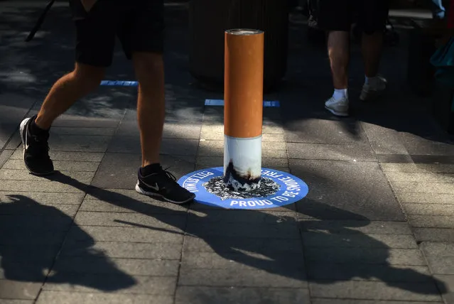 A man walks past a bollard painted to represent a cigarette butt to raise awareness about new 'no smoking' zones in Sydney on September 26, 2016. Sydney's famous shopping district, Pitt Street Mall, is now permanently smoke-free following a similar move at Martin Place in an effort to improve health and air quality in and around the city's shopping malls. (Photo by Saeed Khan/AFP Photo)