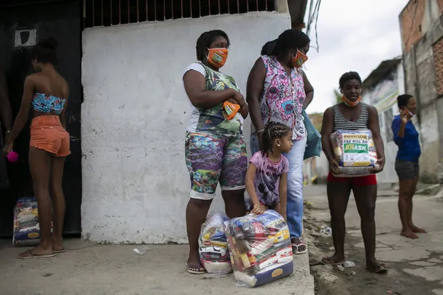 Residents receive donated food from Petrobras workers and the oil workers union via the Tankers’ Campaign that provide a supplement for the poor caught by declining wages and jobs due to the new coronavirus pandemic, in the Vila Vintem neighborhood of Rio de Janeiro, Brazil, Friday, October 16, 2020. (Photo by Bruna Prado/AP Photo)