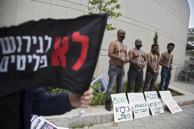 African migrants wear chains to represent slavery during a demonstration in Tel Aviv, Israel, Tuesday, April 3, 2018.  Israel announced a deal with the U.N. on Monday to resettle African migrants in Western nations, but hours later put the agreement on hold. Hebrew sign reads: “No to the deportation of migrants”. (Photo by Sebastian Scheiner/AP Photo)