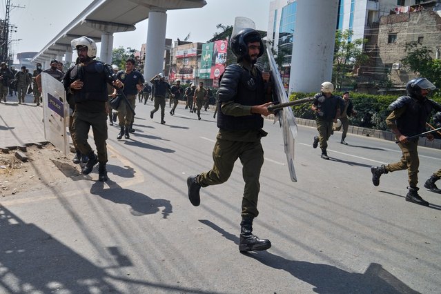 Police personnel run for cover after supporters of Islamist party 'Tehreek-e-Labbaik Pakistan' throw stones toward them during clashes ahead of their pro-Palestinian march toward capital Islamabad, in Lahore, Pakistan, Friday, October 10, 2025. (Photo by K.M. Chaudary/AP Photo)